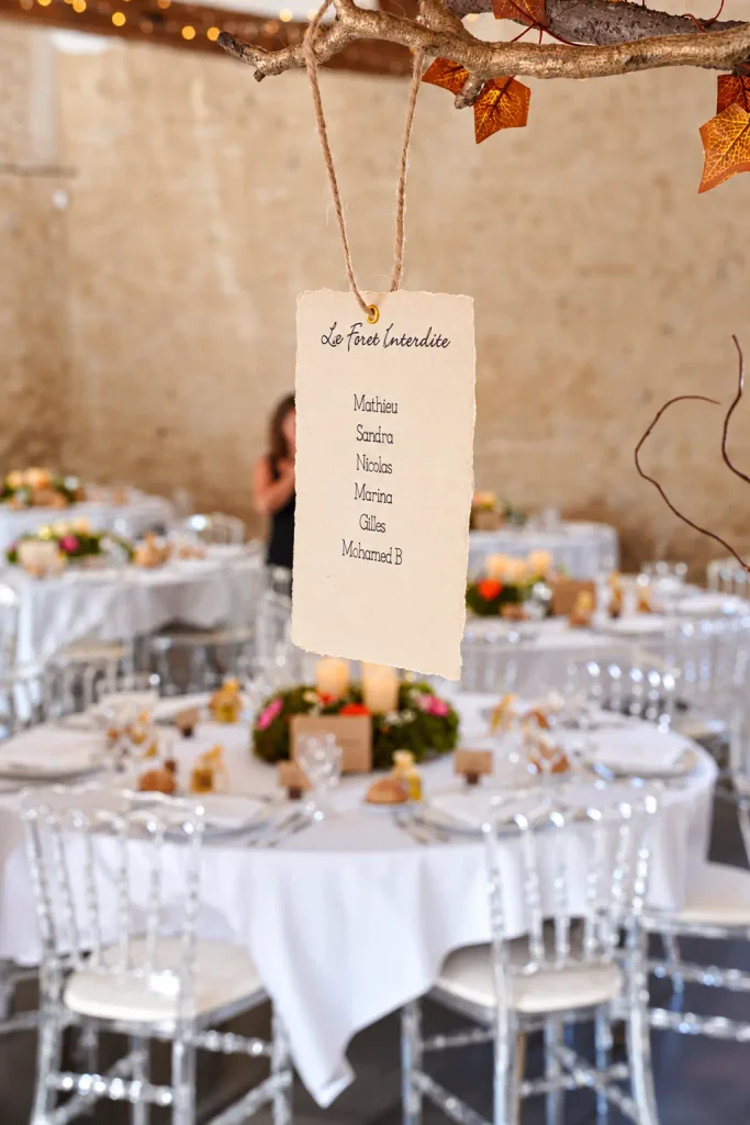 Étiquette du plan de table suspendue à une branche dorée ornée d’une guirlande lumineuse — You You and Me