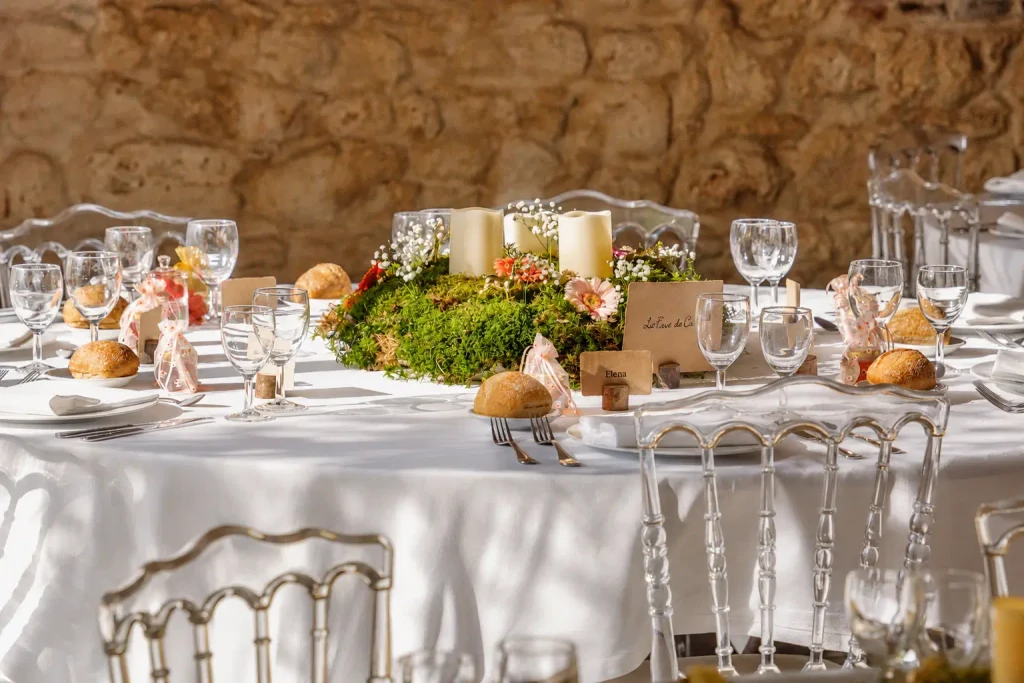 Table de mariage dressée avec nappe blanche, verrerie et marque places sur supports en bois— You You and Me